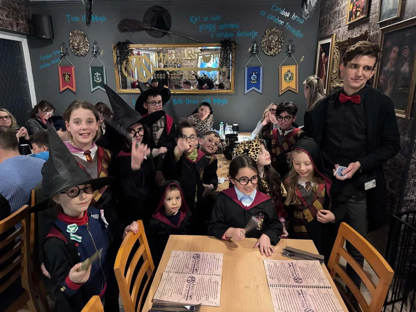 Eine Gruppe von Gästen in Zauberumhängen und Hüten an einem Tisch im Magic Story